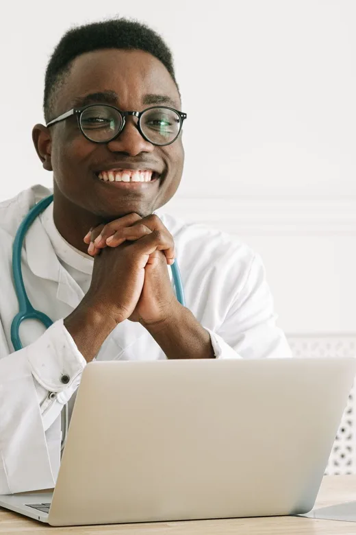 Médico sonriente en su consultorio, con notebook y estetoscopio