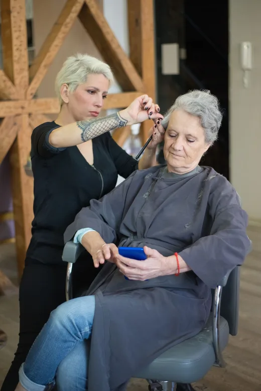 Clienta revisa su teléfono mientras la peluquera le trabaja el pelo en el salón